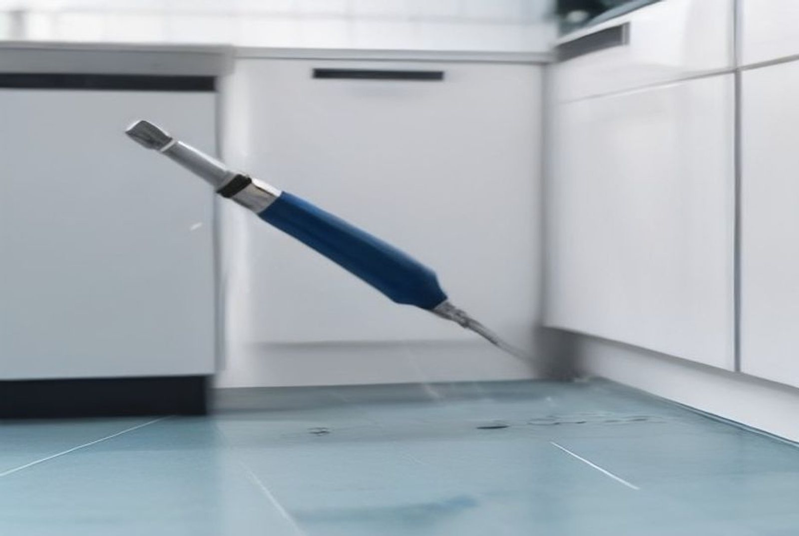 Pest control technician treating the skirting and floor edge of an HDB kitchen in Singapore